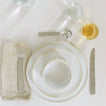 Placesetting with Modernist Dinnerware on white tablecloth.