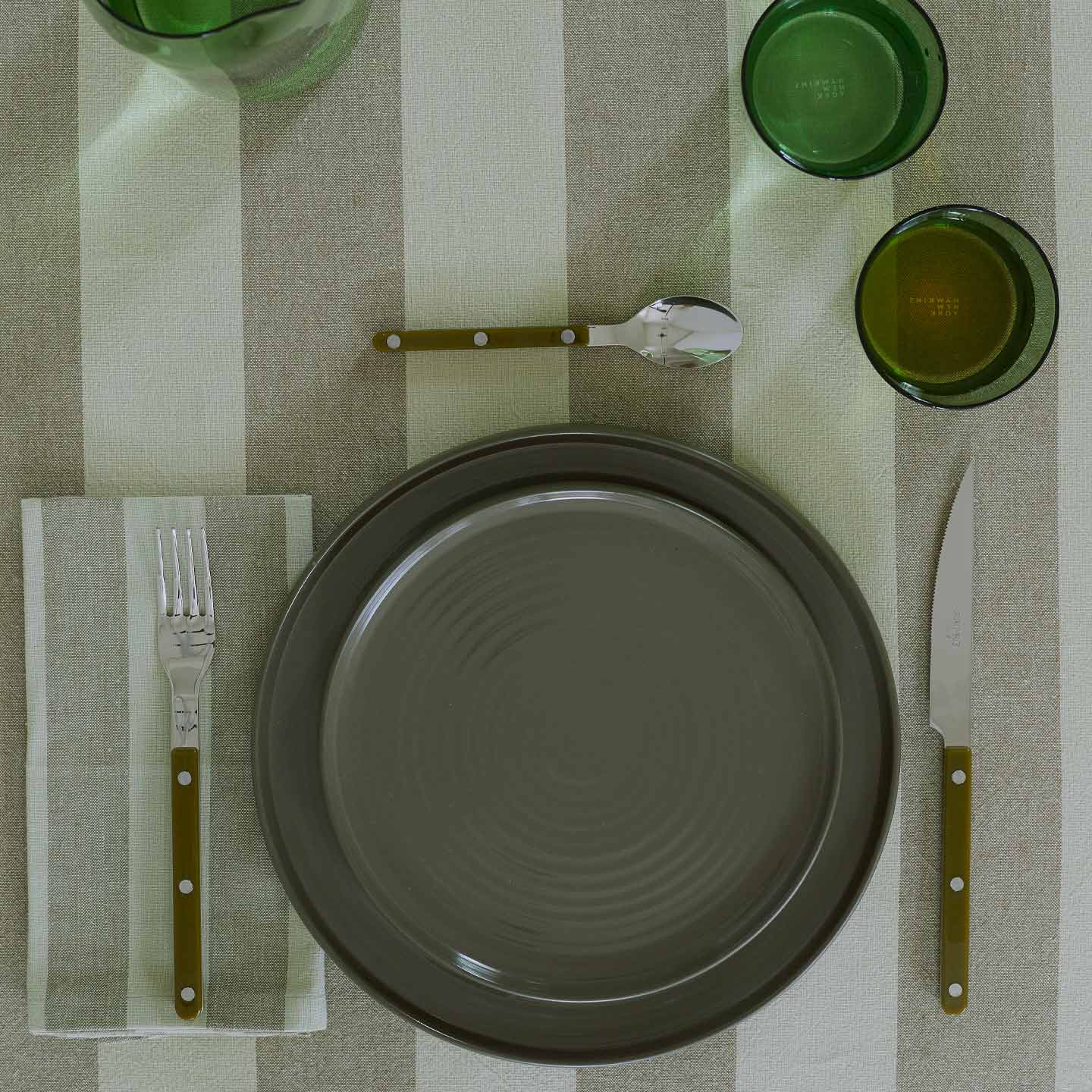 Placesetting with Essential Striped Dinner Napkin in Olive and Sage on Striped Olive tablecloth.