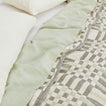 Simple Plaid Blanket in Olive and Sage on a bed with white, ivory, and sage pillows and sheets.