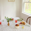 Dining table set with food and drinks in a bright room with a window.