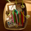 Tray filled with colorful pens, markers, and art supplies on a wooden surface.