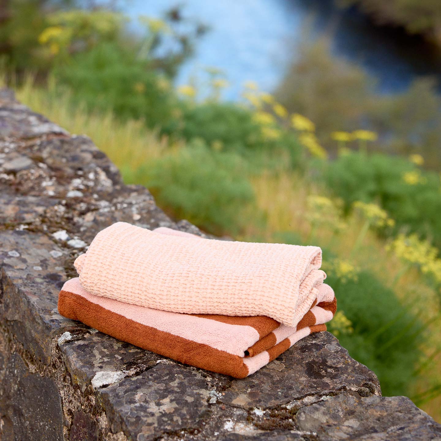 Folded towels on a stone ledge with a natural background