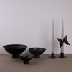A trio of footed bowls and pair of candle holders, all in Black, with grey taper candles. Styled with a butterfly.