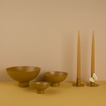 A trio of footed bowls and pair of candle holders, all in Mustard, with honey taper candles. Styled with a butterfly.