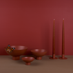 A trio of footed bowls and pair of candle holders, all in Terracotta, with red-orange taper candles. Styled with a butterfly.