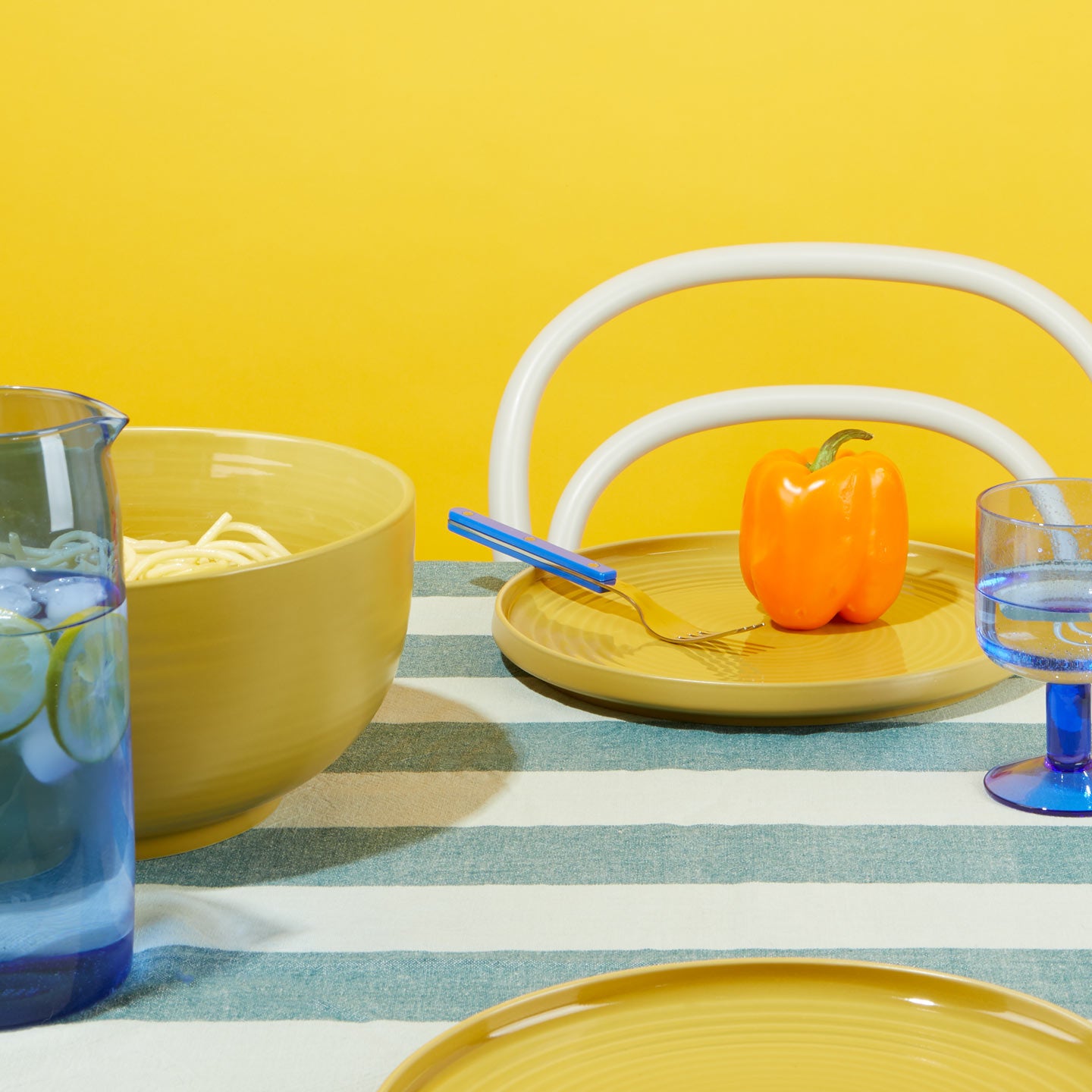 Essential Tabletop setting with Essential Dinnerware in Mustard and Essential Glass Pitcher in Blue.
