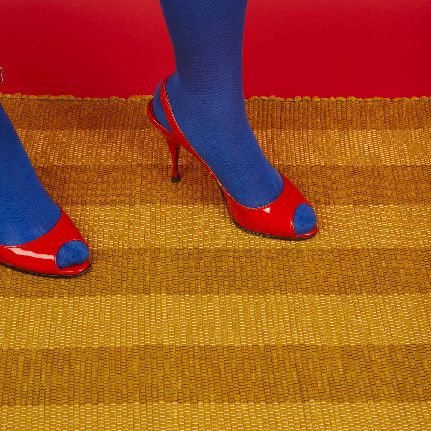 Red high-heeled shoes with blue toes Essential Floor Mat in Mustard with red background.