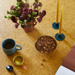 Cork surface with a cup of coffee, bowl of nuts, and flowers.