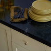 Yellow plates, black forks, and a brown napkin on a dark countertop with beige cabinets.