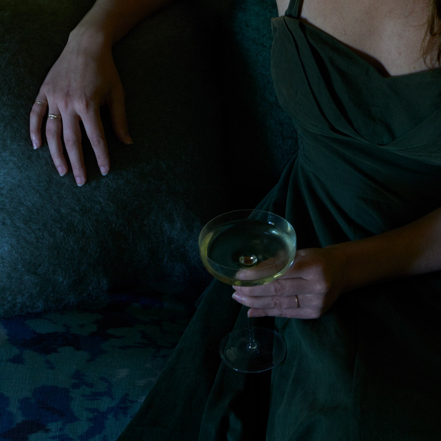Person holding a glass of champagne on a dark background