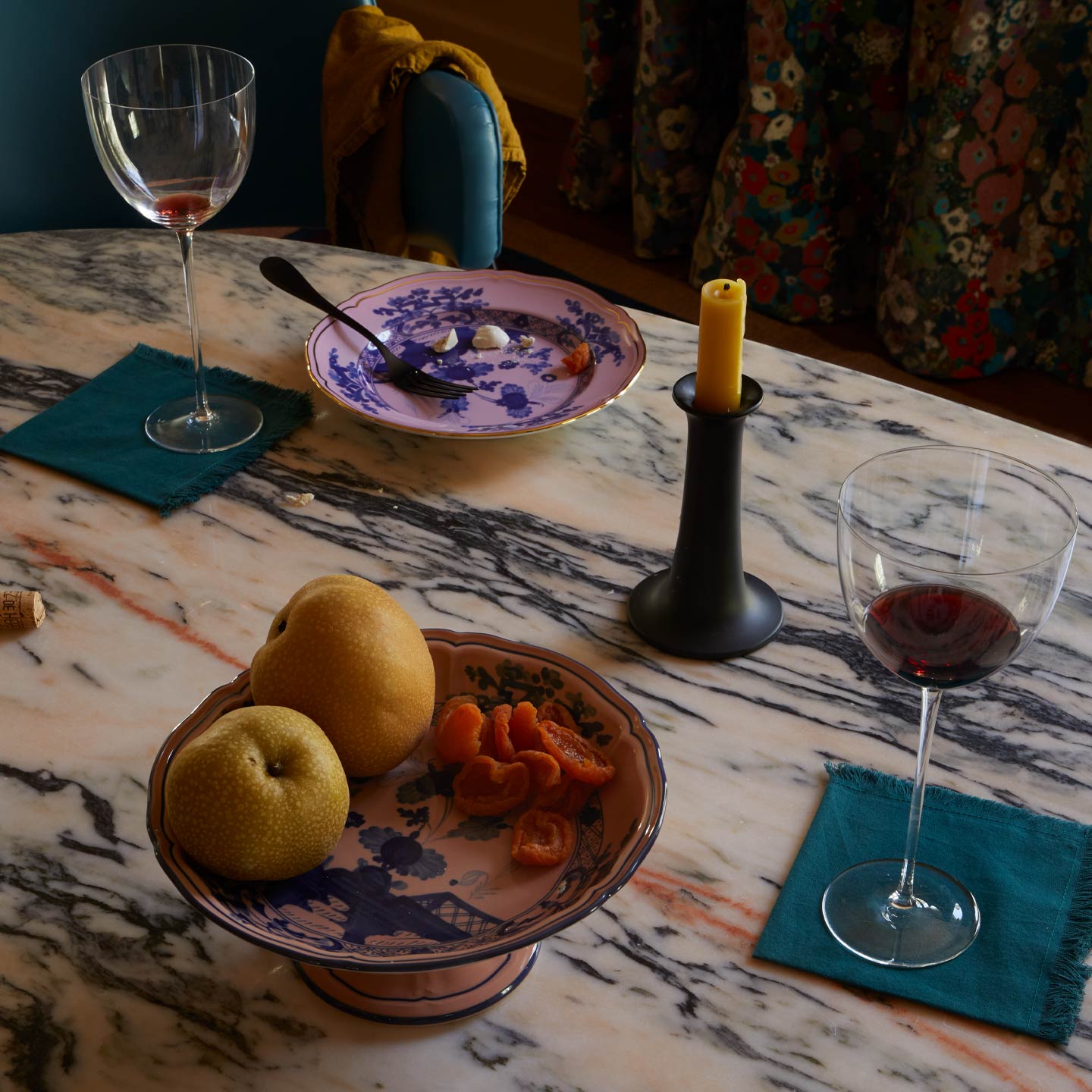 Table setting with wine glasses, plates, and candles on a marble surface.