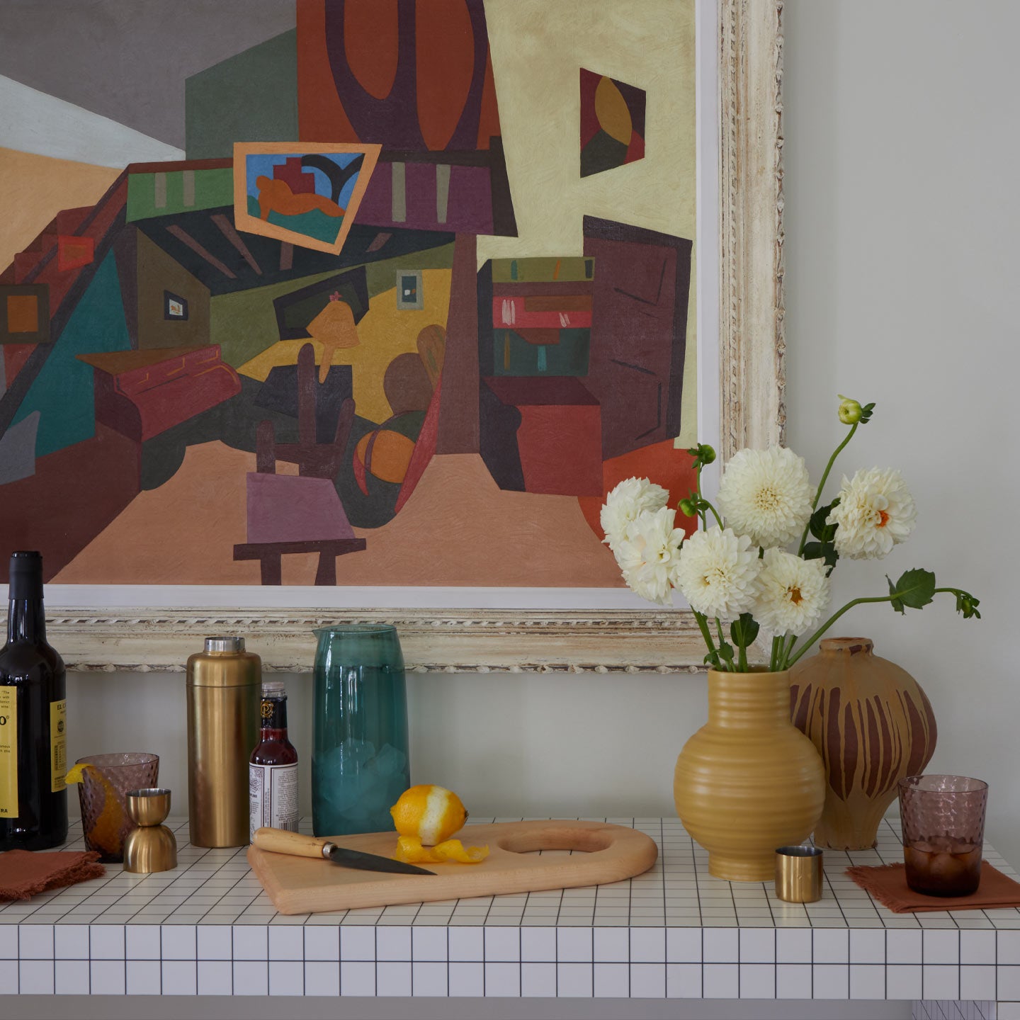 Decorative bar shelf with vases, a cutting board, and a colorful abstract painting.