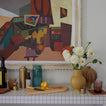 Decorative bar shelf with vases, a cutting board, and a colorful abstract painting.