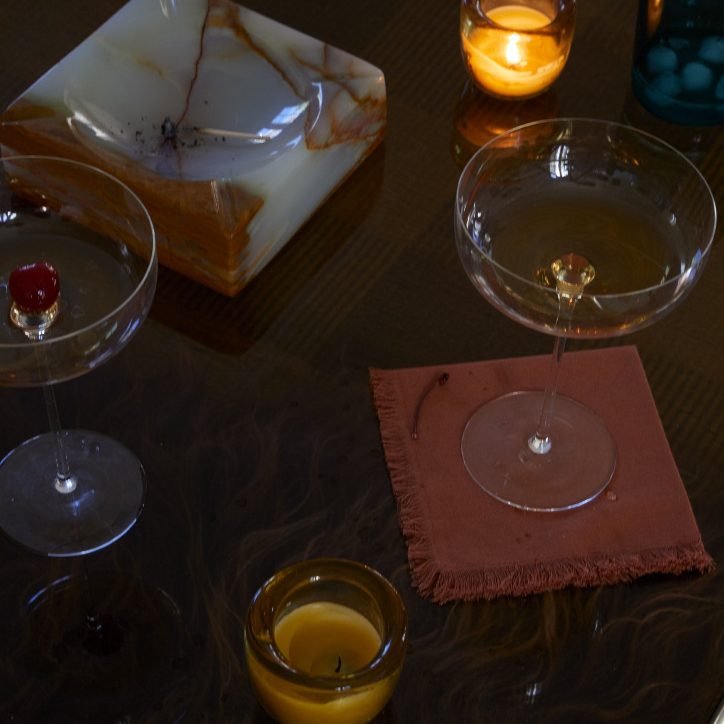 Cocktail glasses on a dark surface with a candle