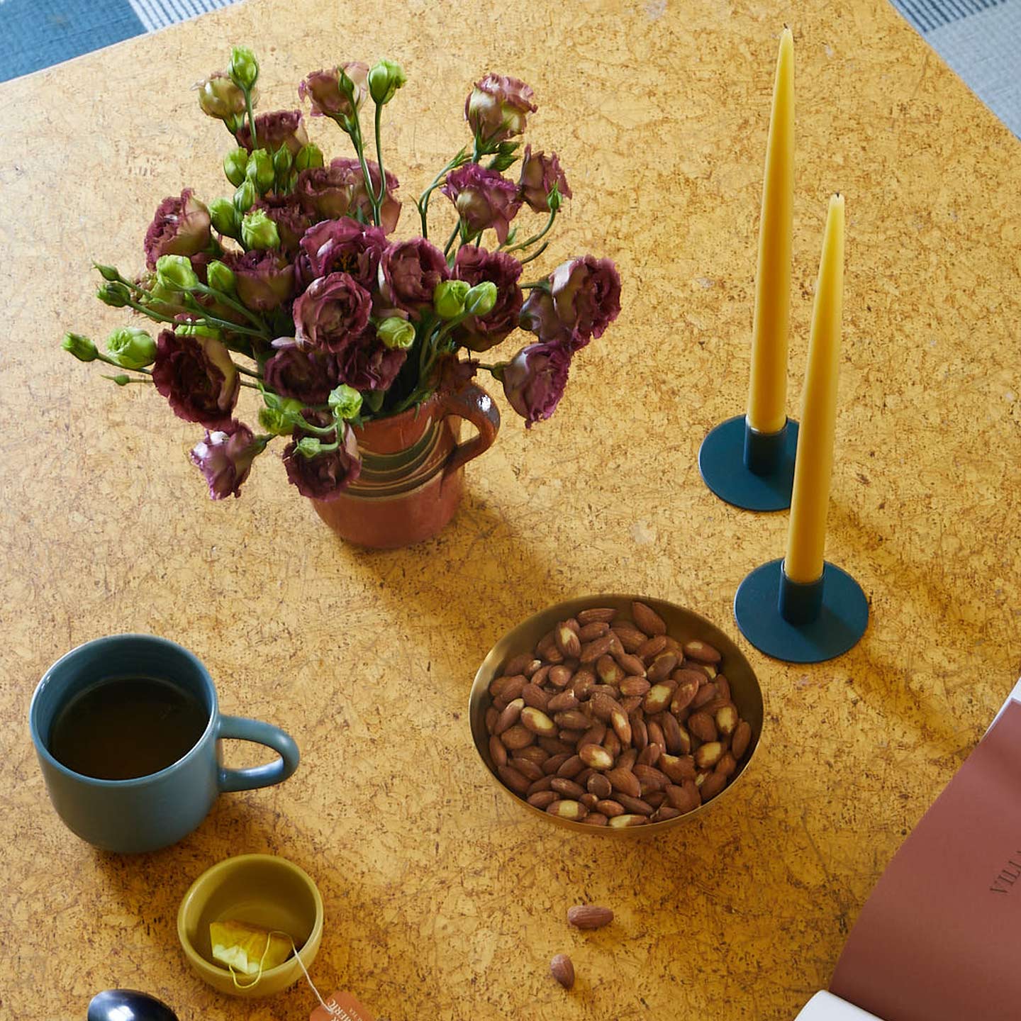 Peacock colored coffee mug on table with vase, florals, and candle sticks