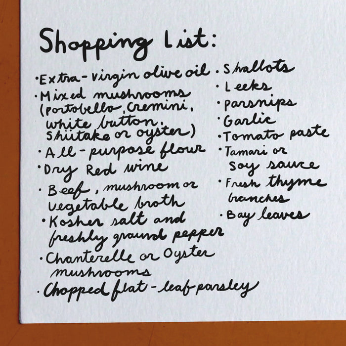 A handwritten shopping list on white paper includes items such as extra-virgin olive oil, mixed mushrooms, all-purpose flour, dry red wine, garlic, tomato paste, and fresh thyme branches.