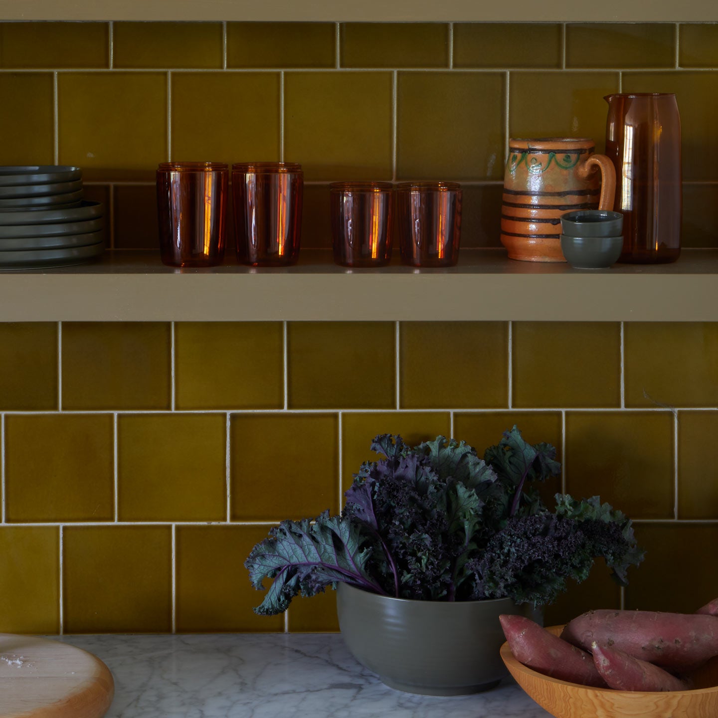 Kitchen shelves with bowls and produce and Essential Glass Pitcher and Glassware in Terracotta and Essential Plates in Olive.