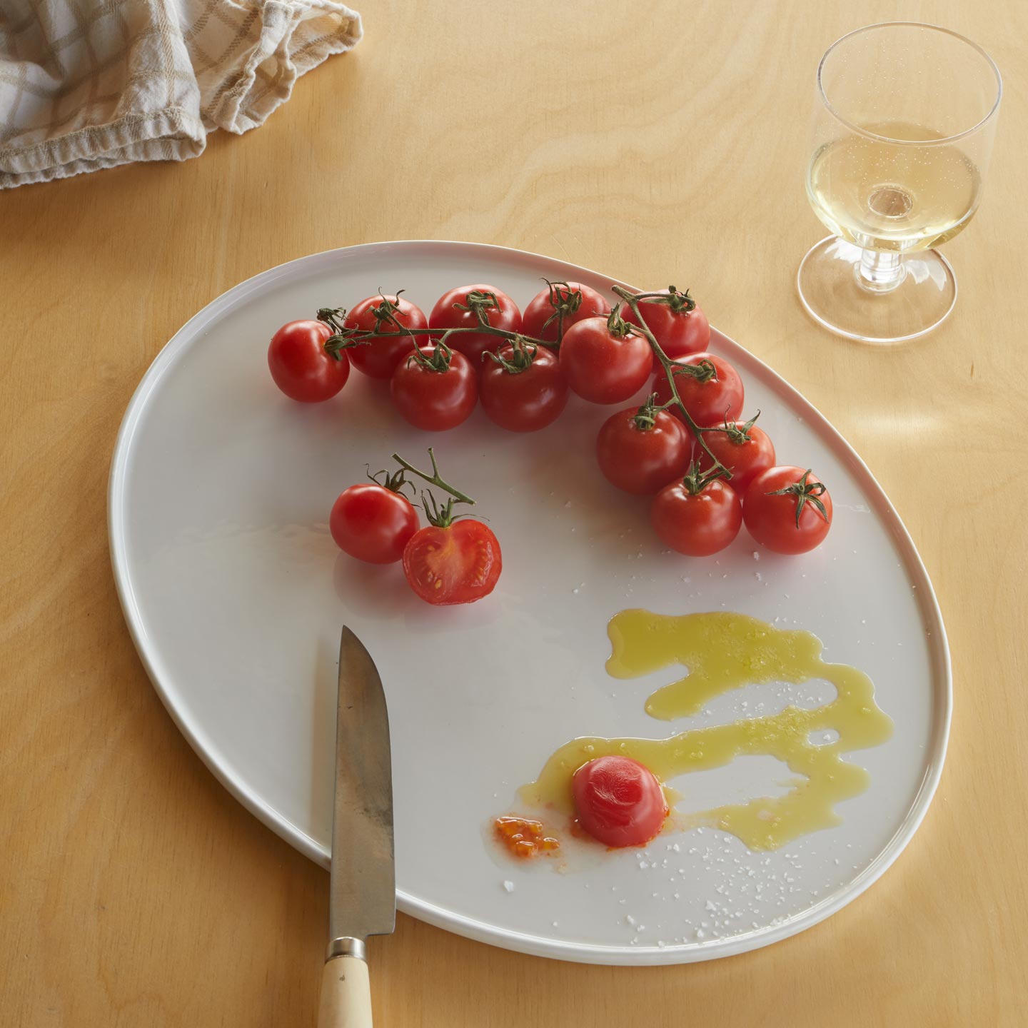 Simple Porcelain Platter with tomatoes and olive oil and knife and simple seeded glass.
