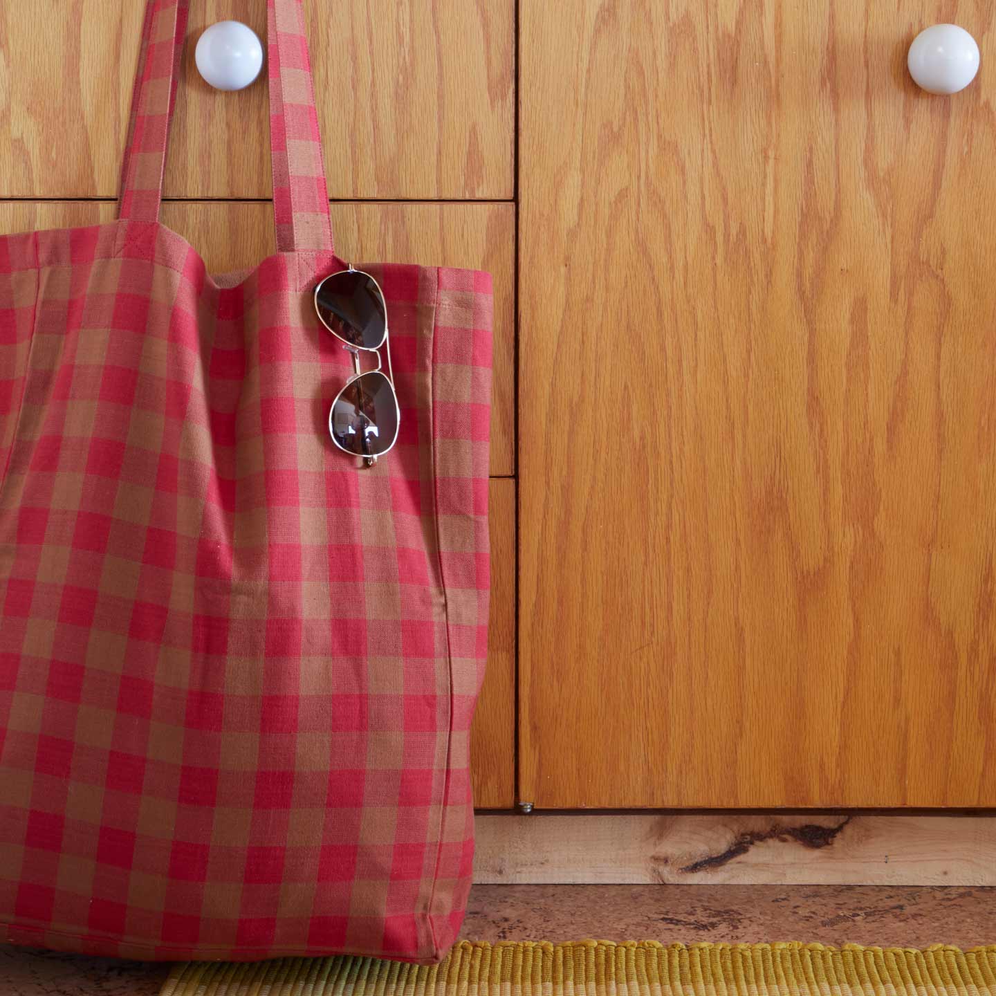 Essential Gingham Tote in Red hanging on knob with sunglasses tucked in.
