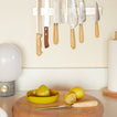 Knives with wooden handles hanging on a magnetic strip above a kitchen counter with lemons and a juicer.