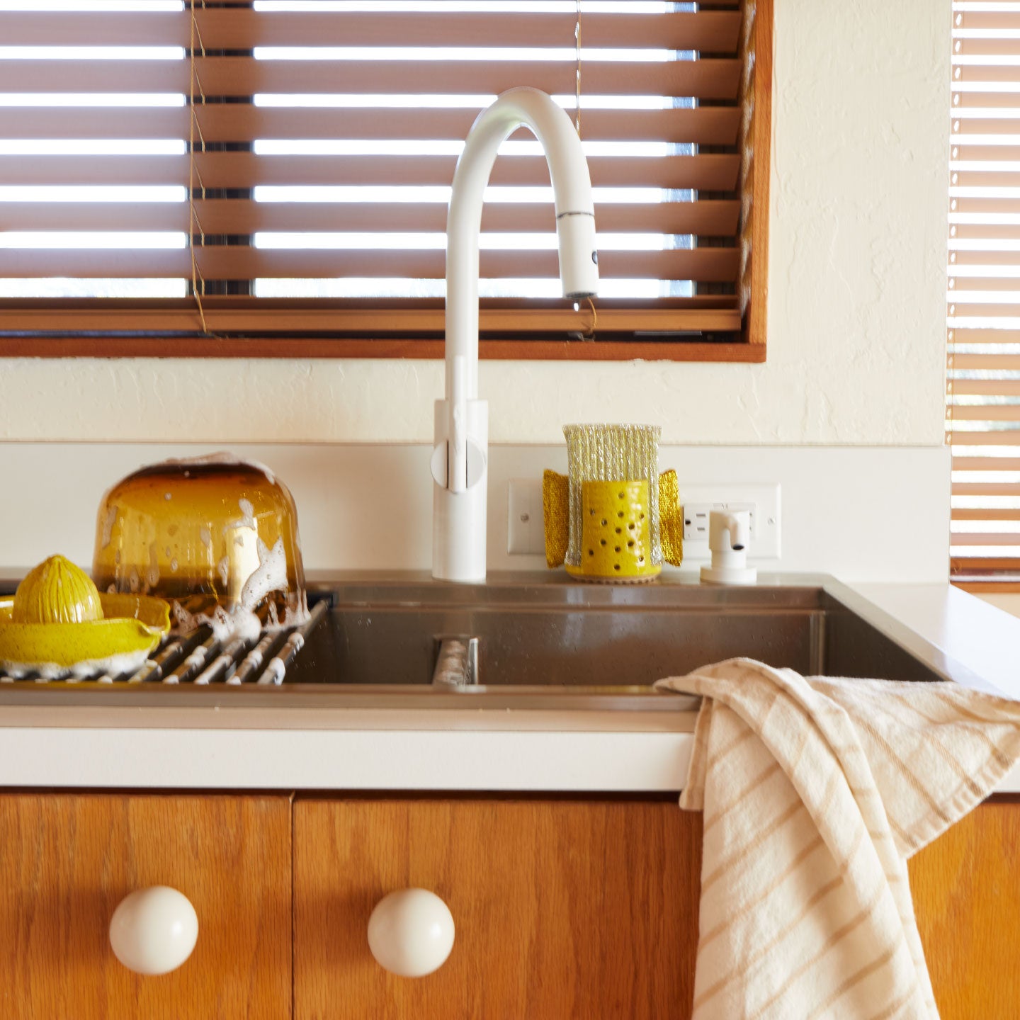 Modern kitchen sink with yellow glass items and wooden cabinets and Essential Ivory Dishtowel.