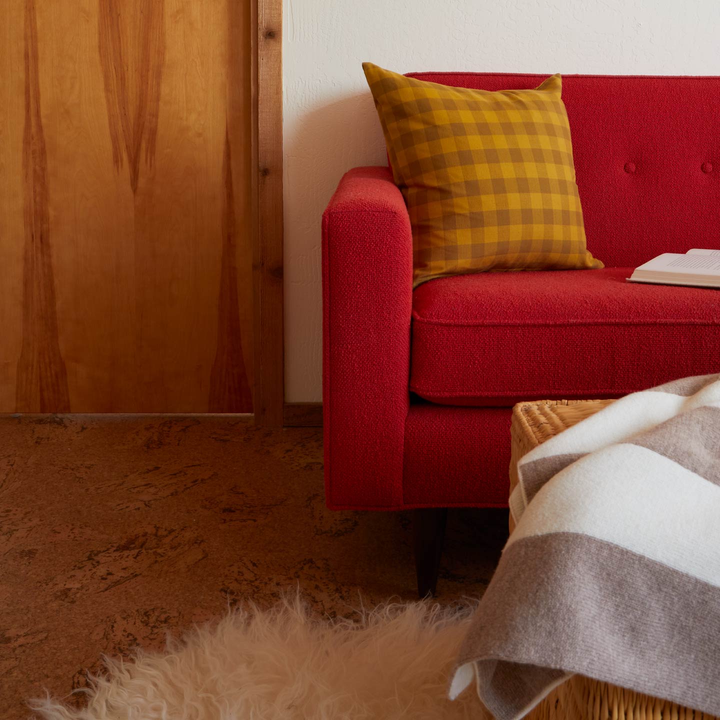 Red sofa with a yellow gingham pillow in a cozy living room setting.