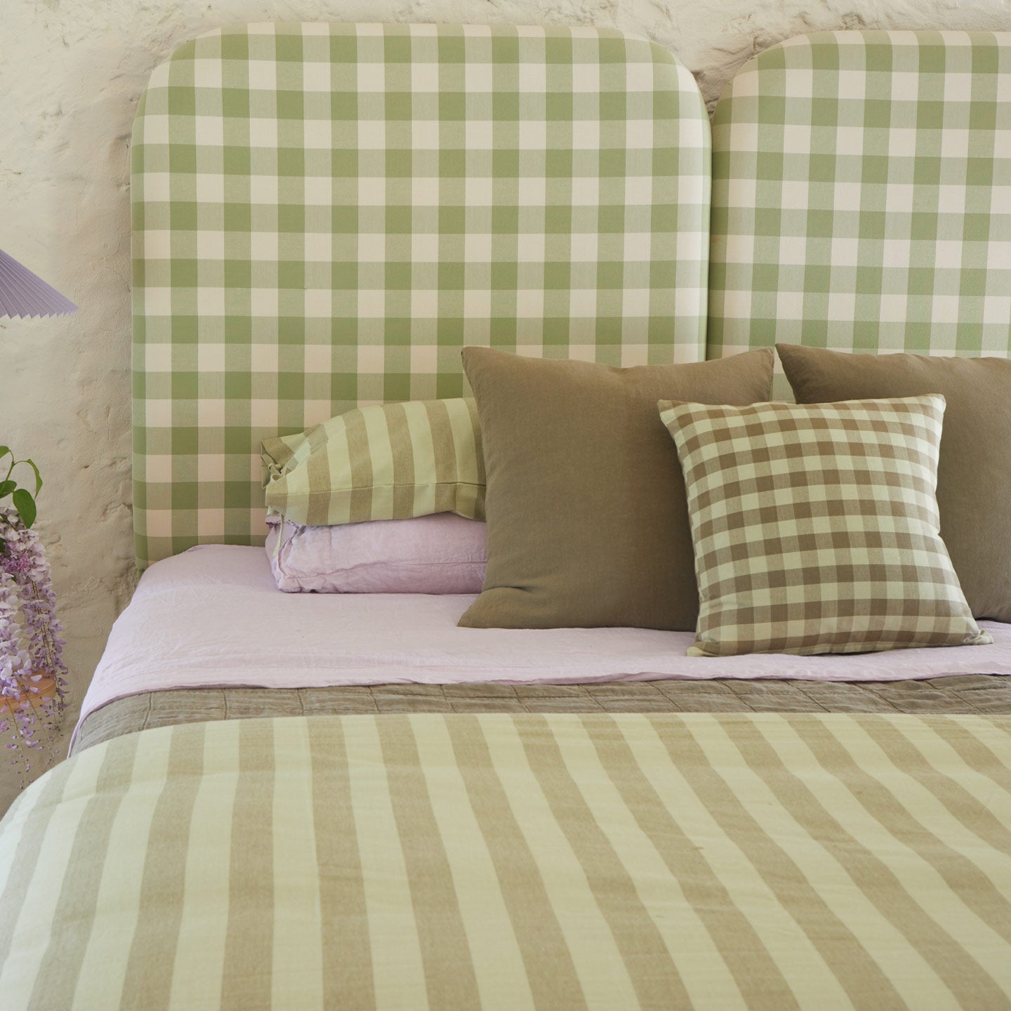Bed with green and lilac bedding in stripes and gingham.