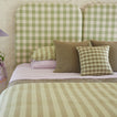 Bed with green and lilac bedding in stripes and gingham.