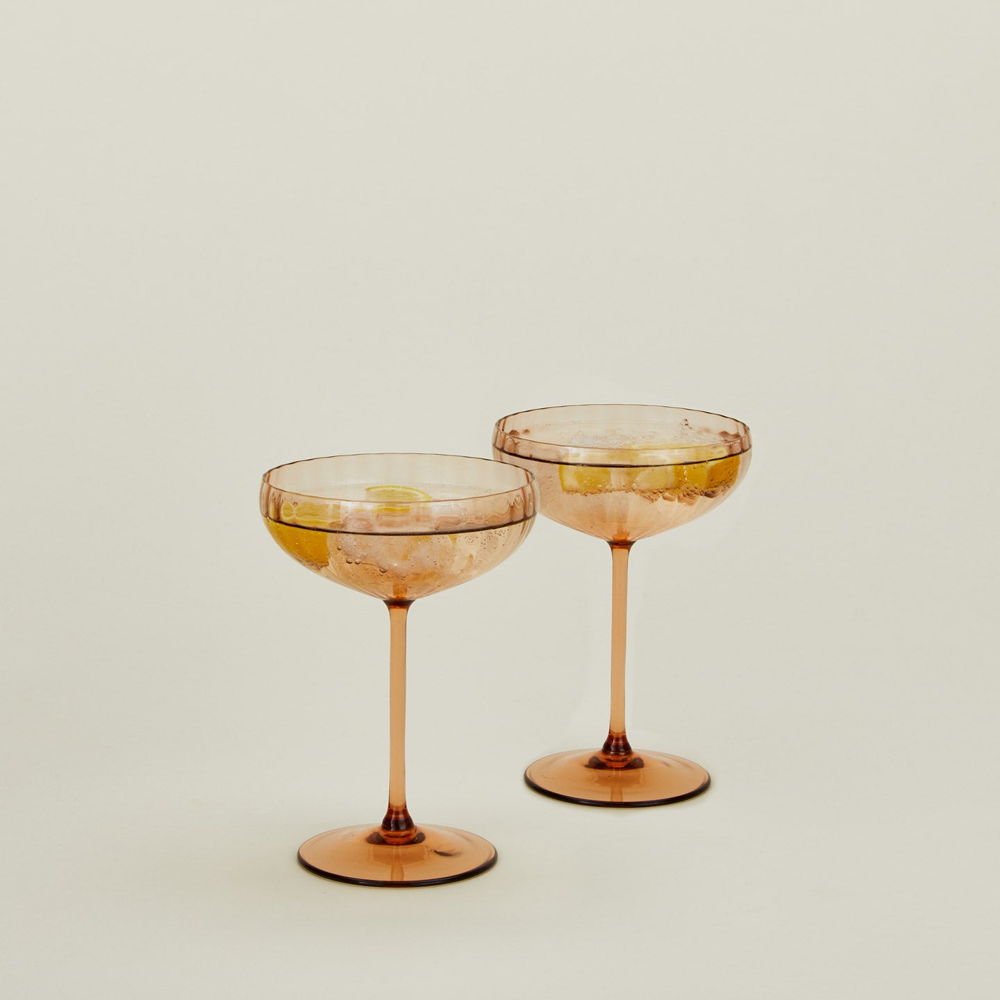 Set of two ribbed brown coupe glasses with cocktail.