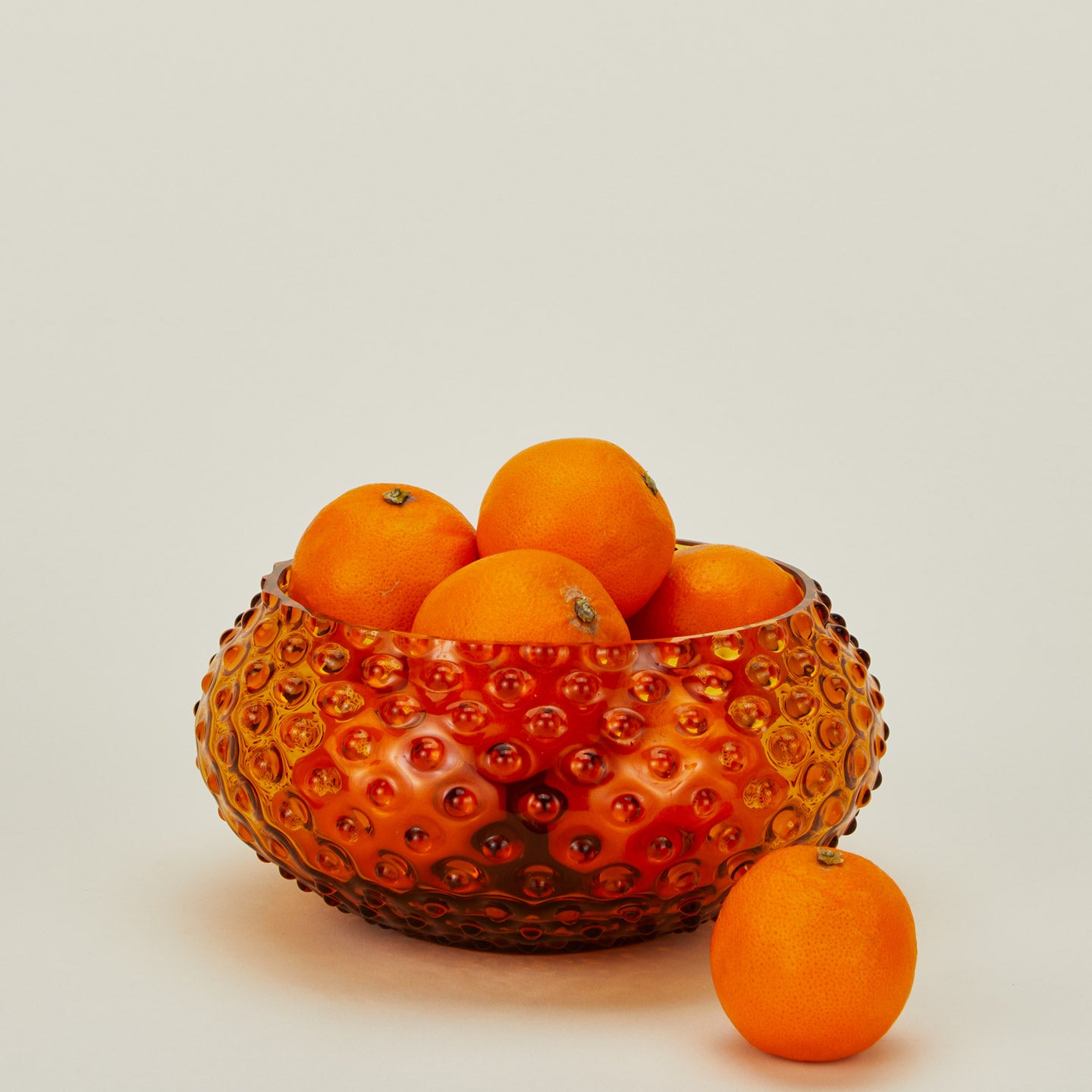 Glass hobnail amber serving bowl with oranges.