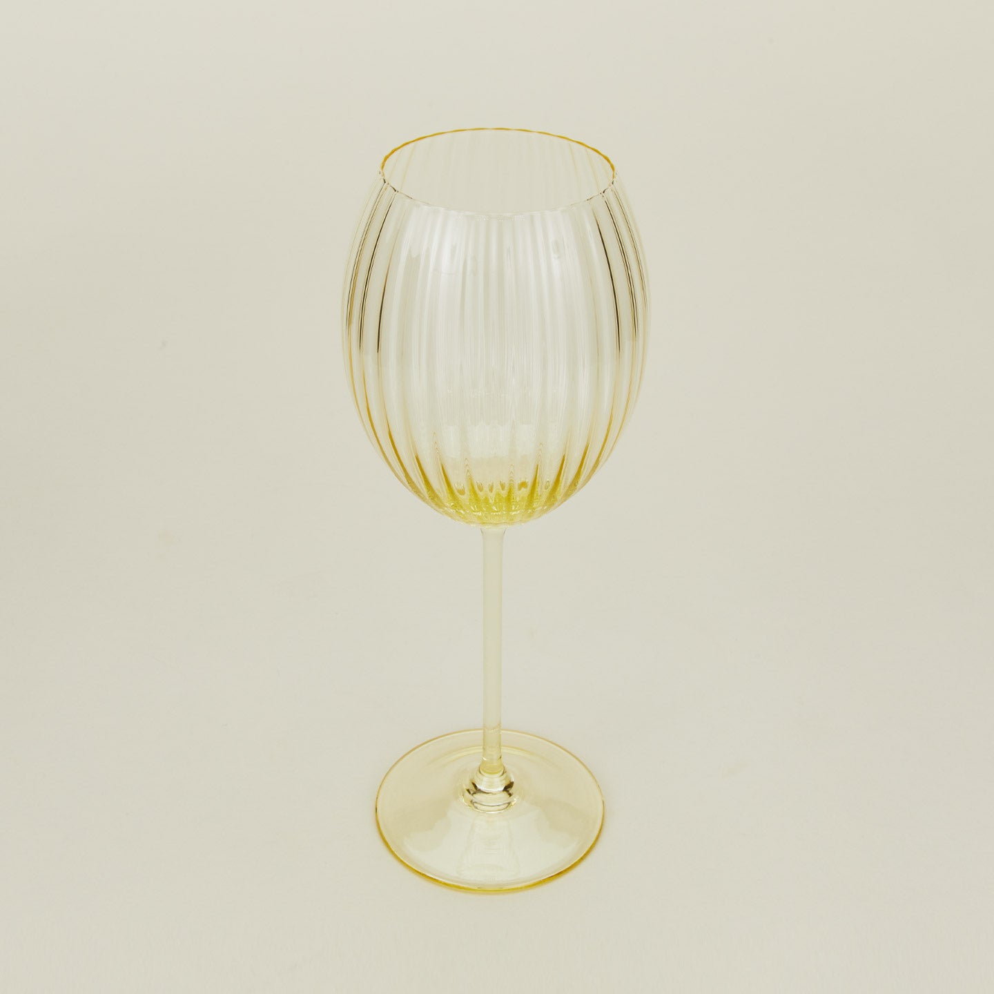 Three-quarter angle of ribbed amber wine glass.