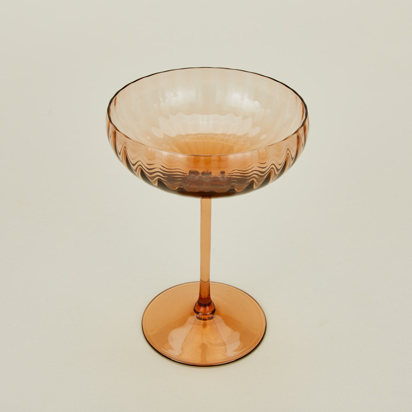 Three-quarter angle of ribbed brown coupe glass.