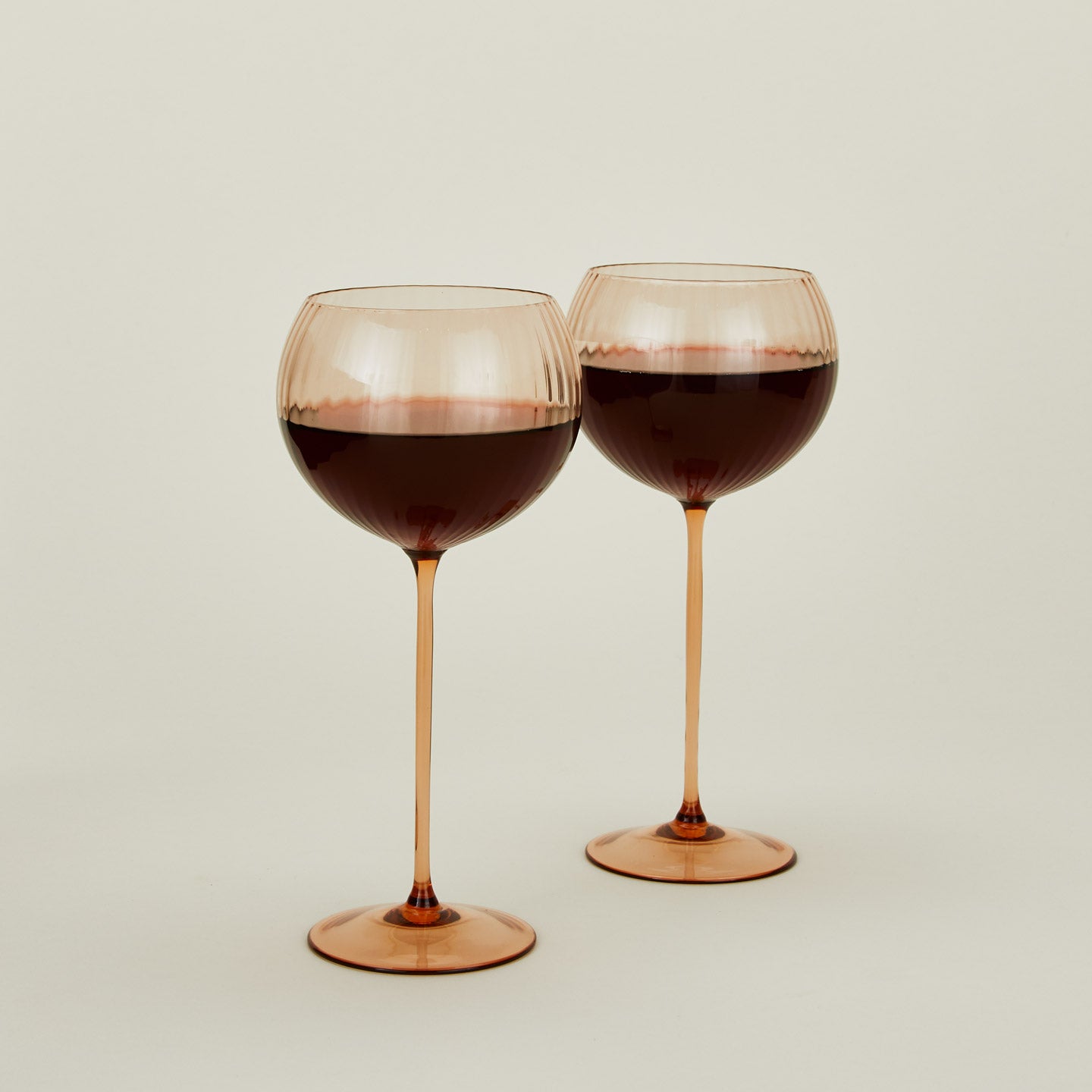 Set of two ribbed brown wine glasses with red wine.