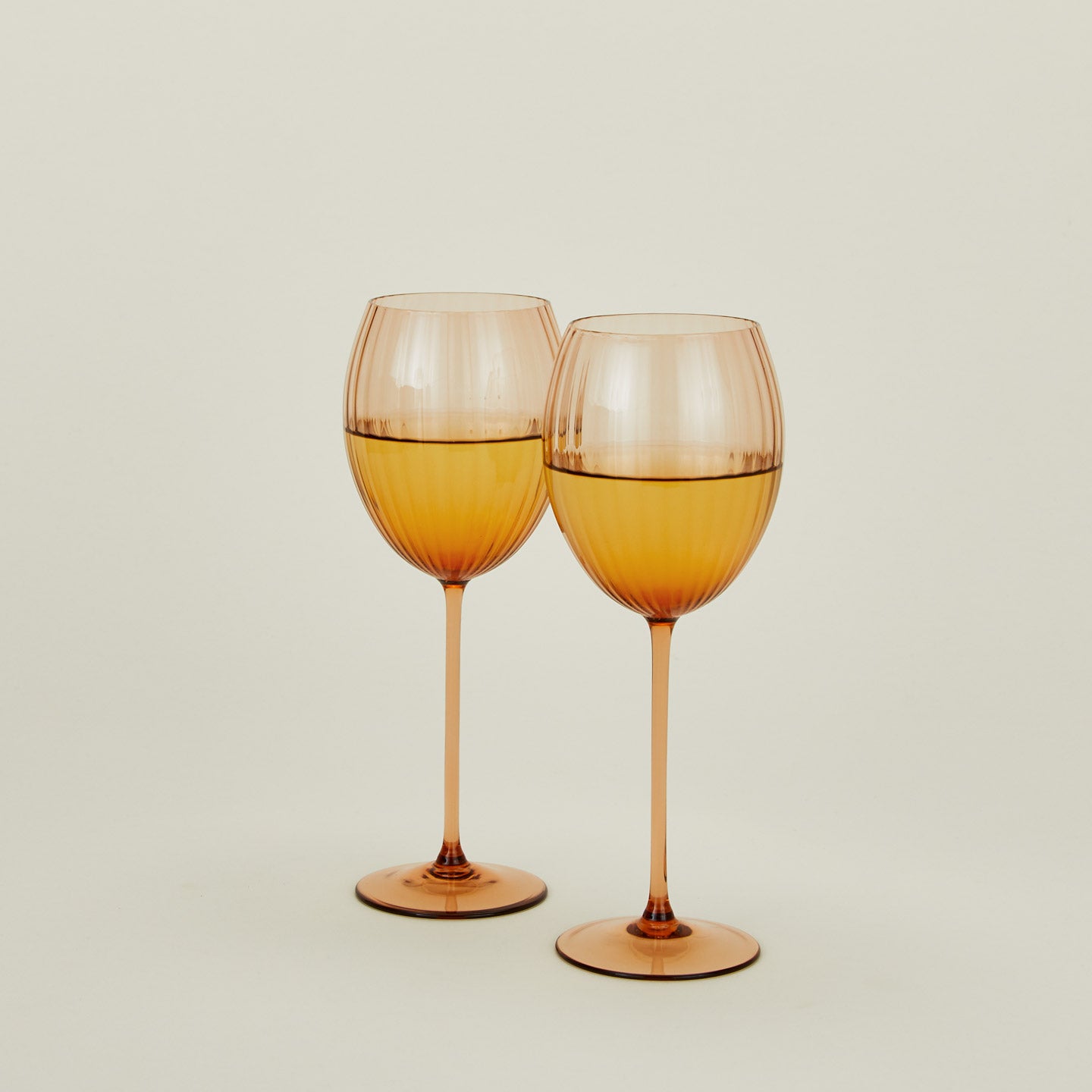 Set of two ribbed brown wine glasses with white wine.