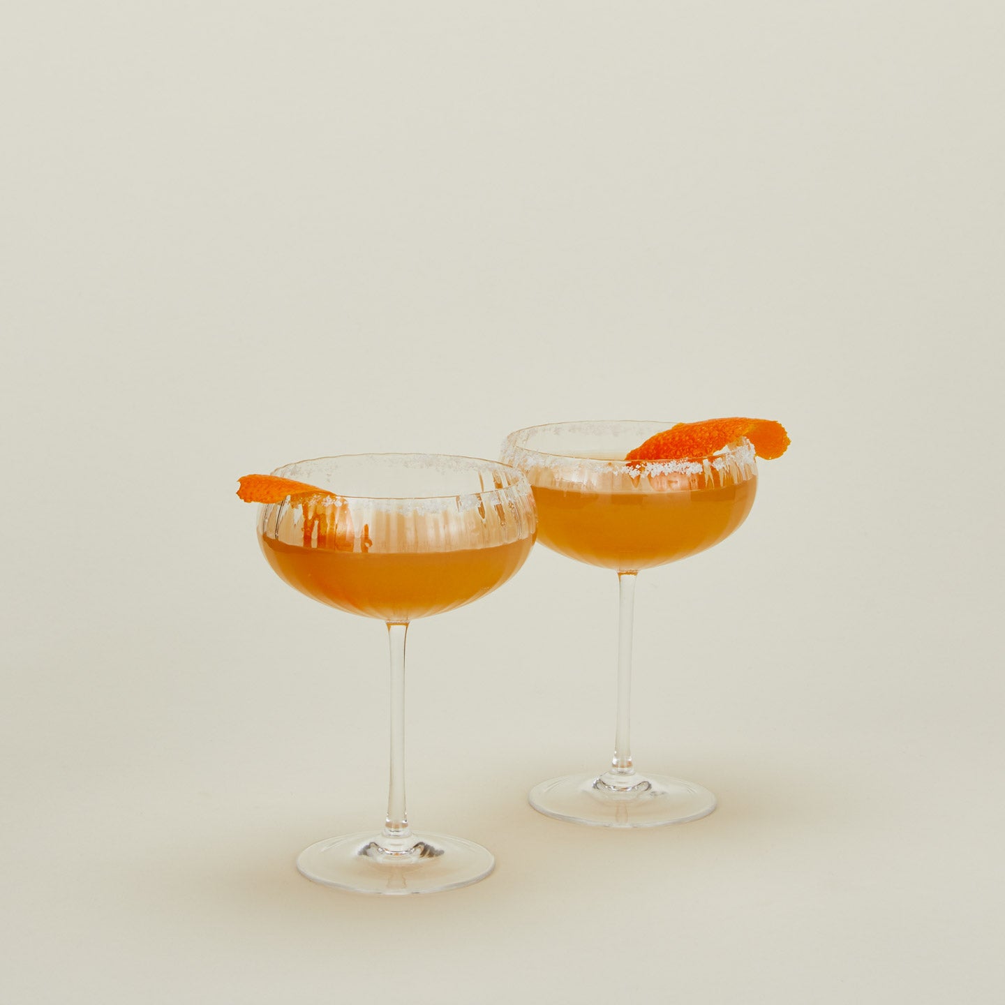 Set of two ribbed clear coupe glasses with cocktail.