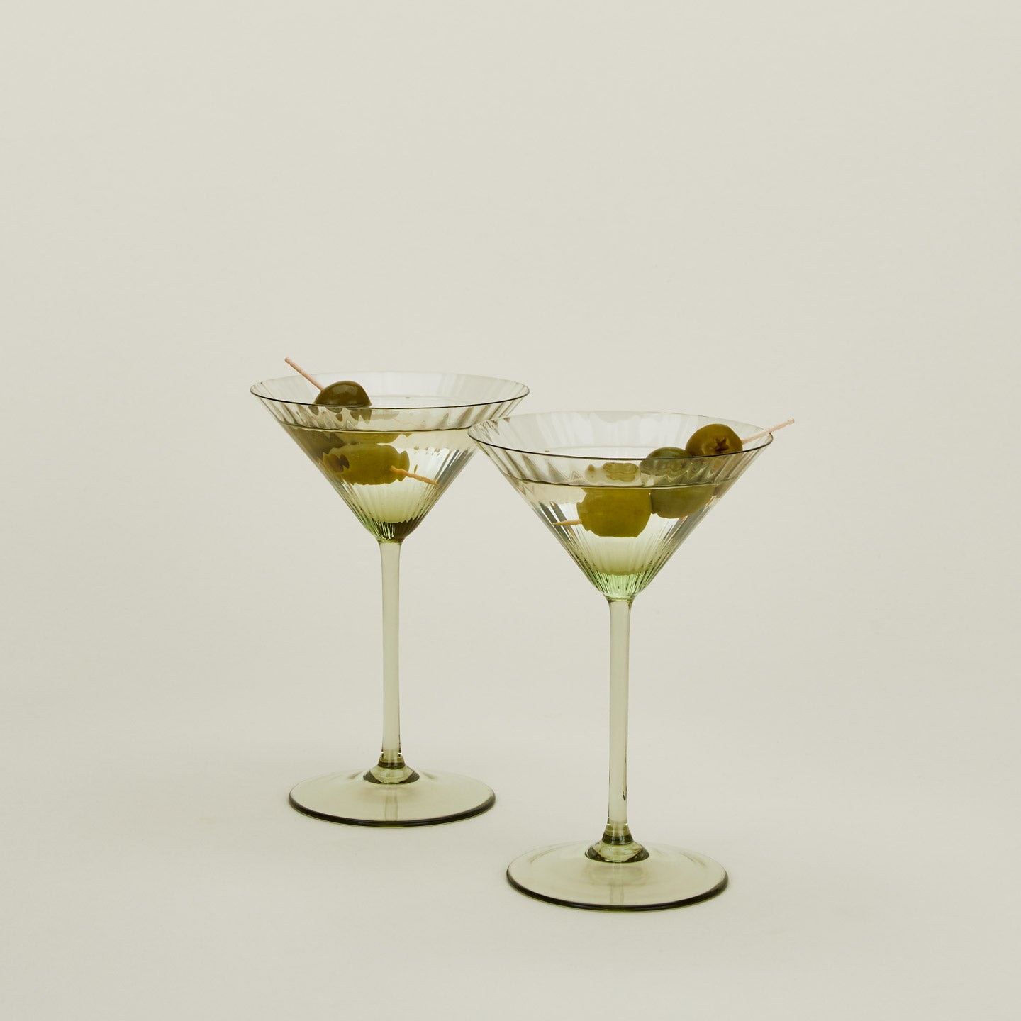 Set of two ribbed olive martini glasses with cocktail.