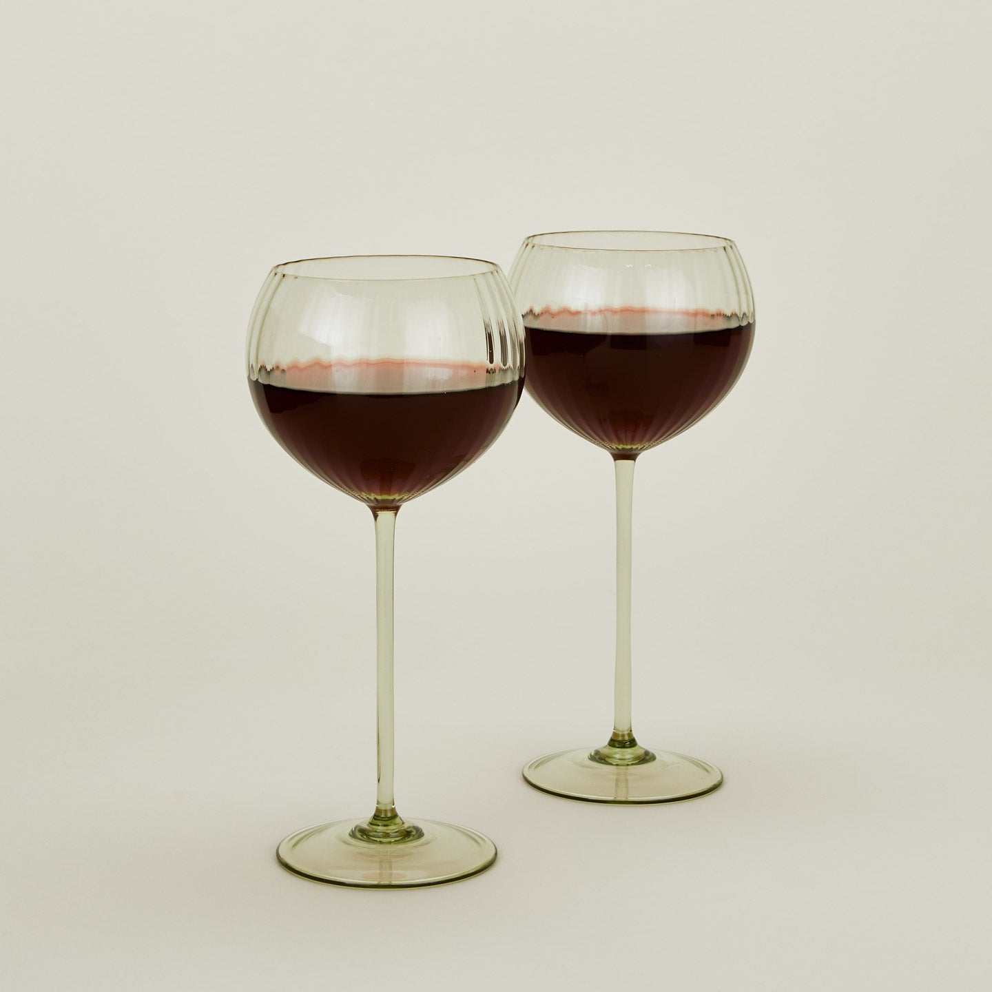 Set of two ribbed  olive wine glasses with red wine.