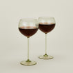 Set of two ribbed  olive wine glasses with red wine.