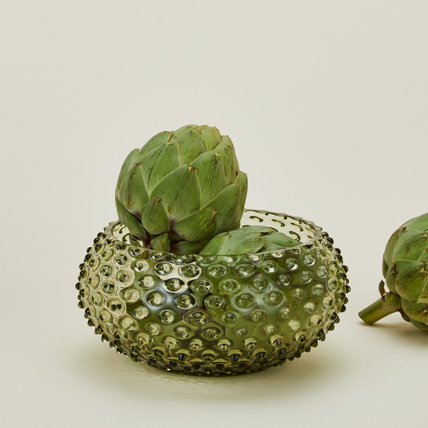 Glass hobnail olive serving bowl with artichokes.