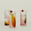 Three Blown Glass Highballs in Blush and Amber, filled with water and garnished with cherries.