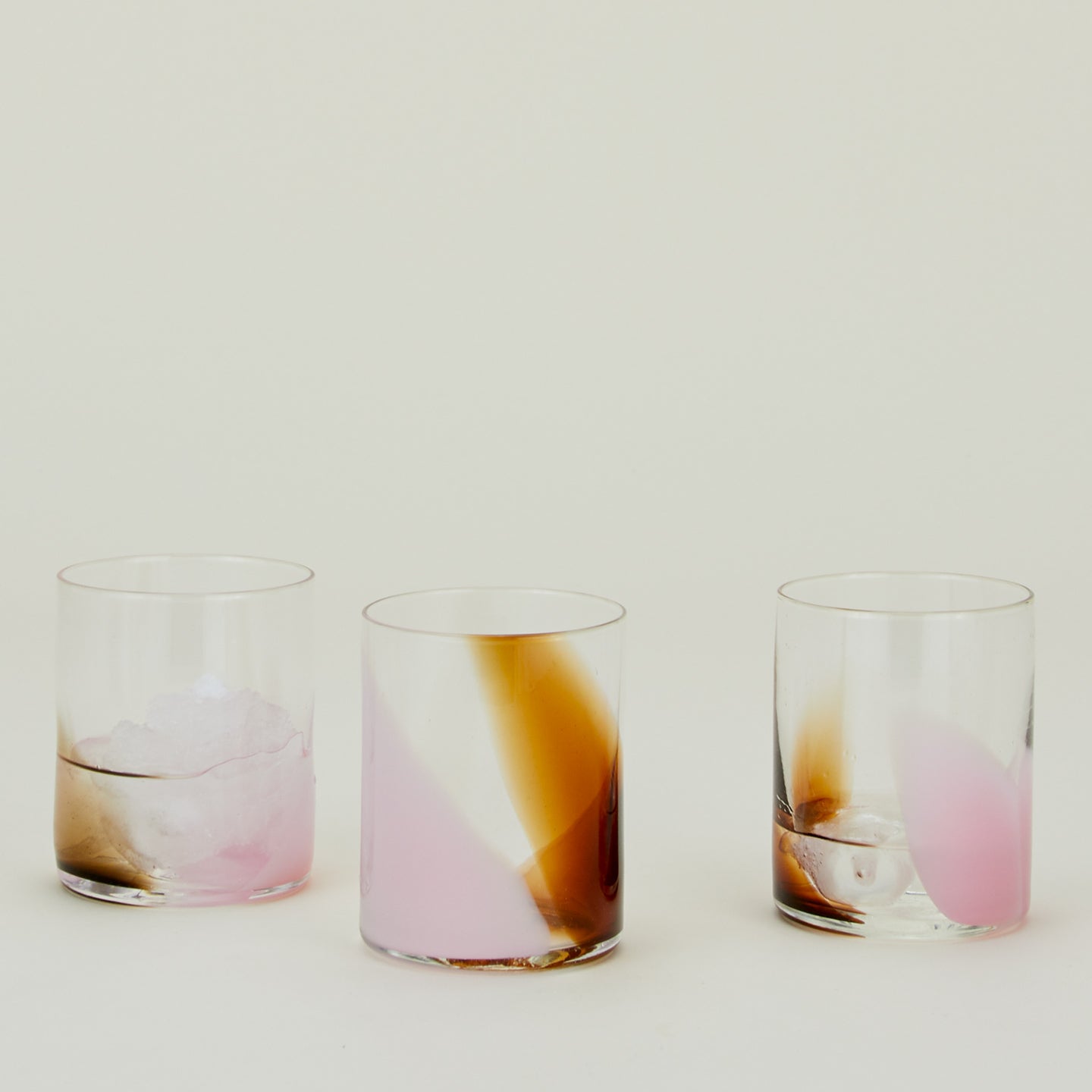 Three Blown Glass Tumblers in Blush and Amber, filled with ice water.