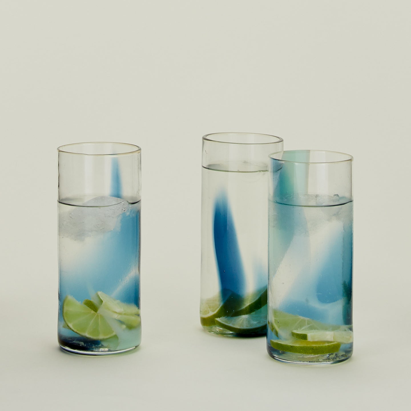 Three Blown Glass Highballs in Sky and Peacock, filled with water.