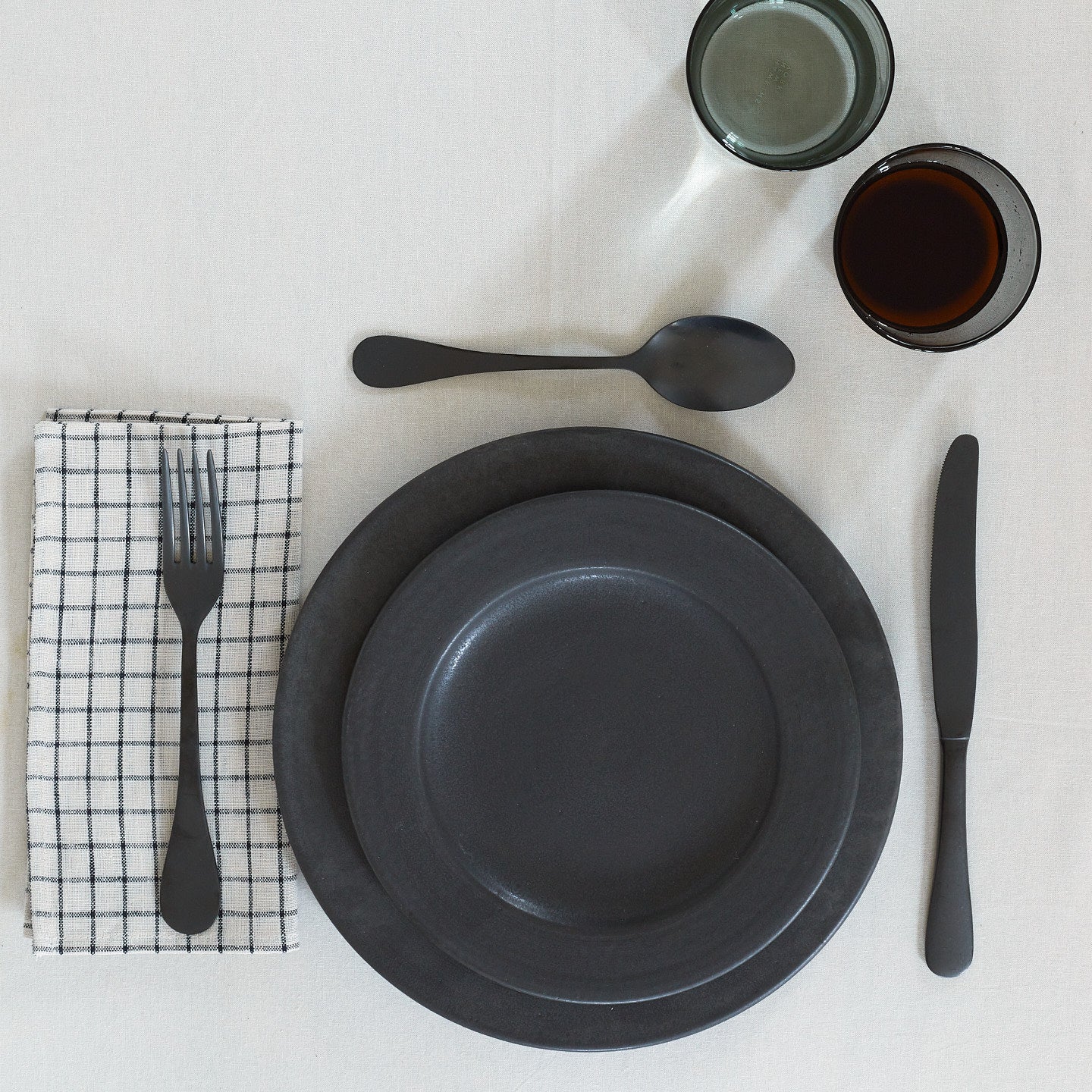 Placesetting with Checked Linen Napkin on white tablecloth.