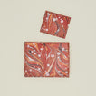 Overhead view of two scalloped marbled trays in red.