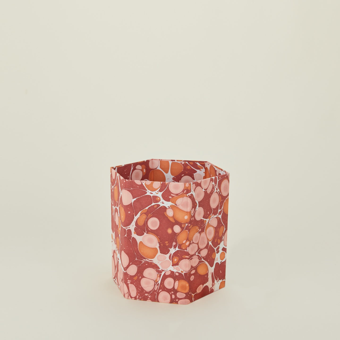 Marbled hexagon wastebasket in warm tones.