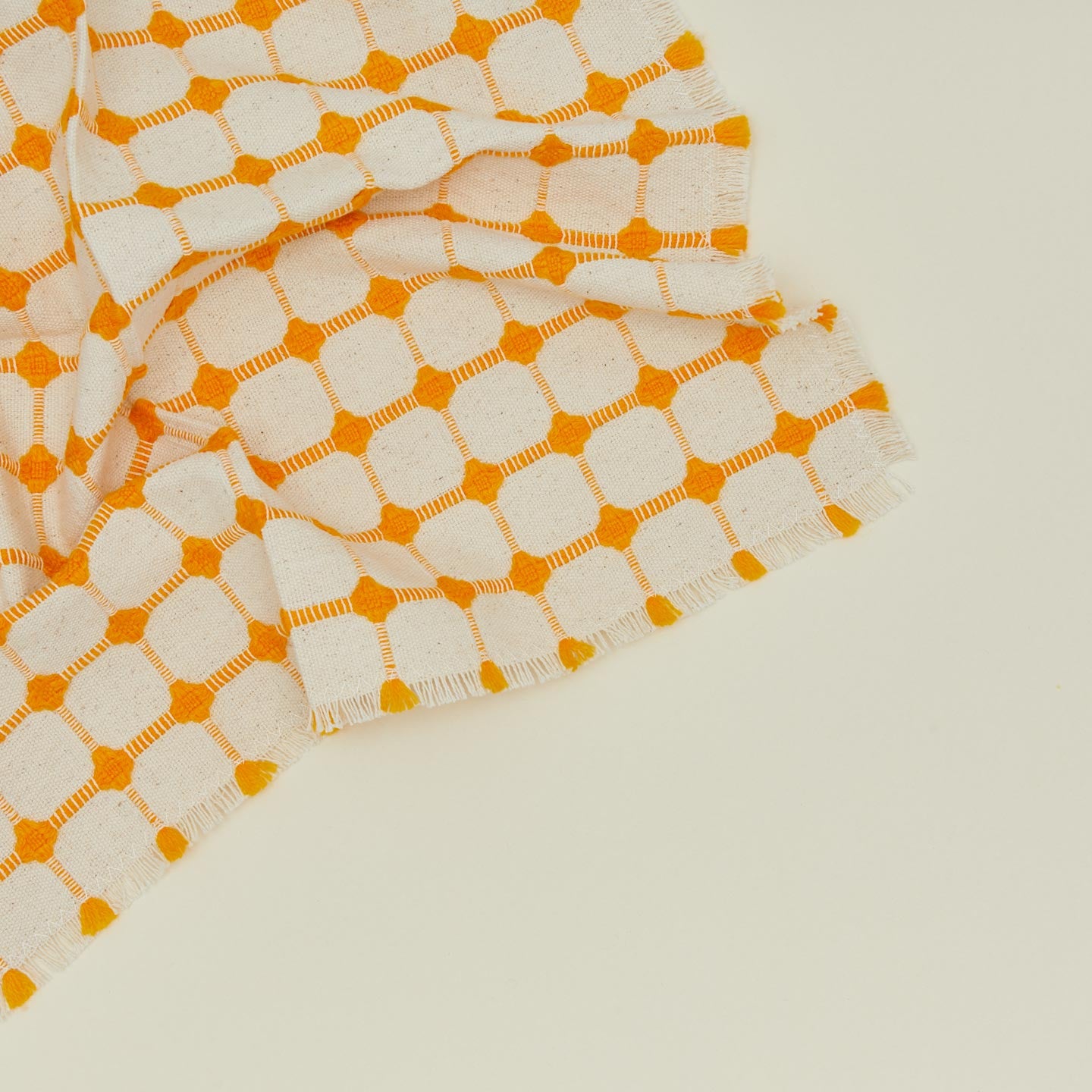 Close up view of Dove and Donkey wicker fringed napkin in marigold