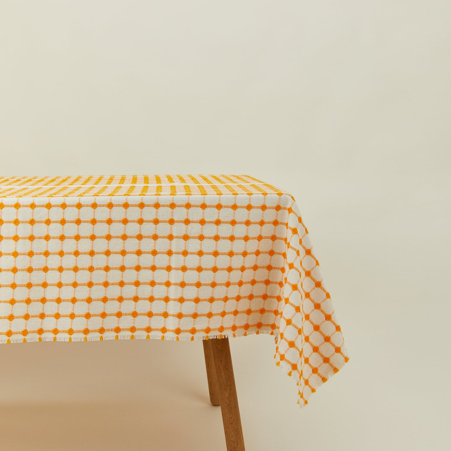 Dove and Donkey wicker fringed tablecloth in marigold on table