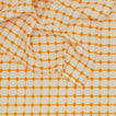 Close up view of Dove and Donkey wicker fringed tablecloth in marigold