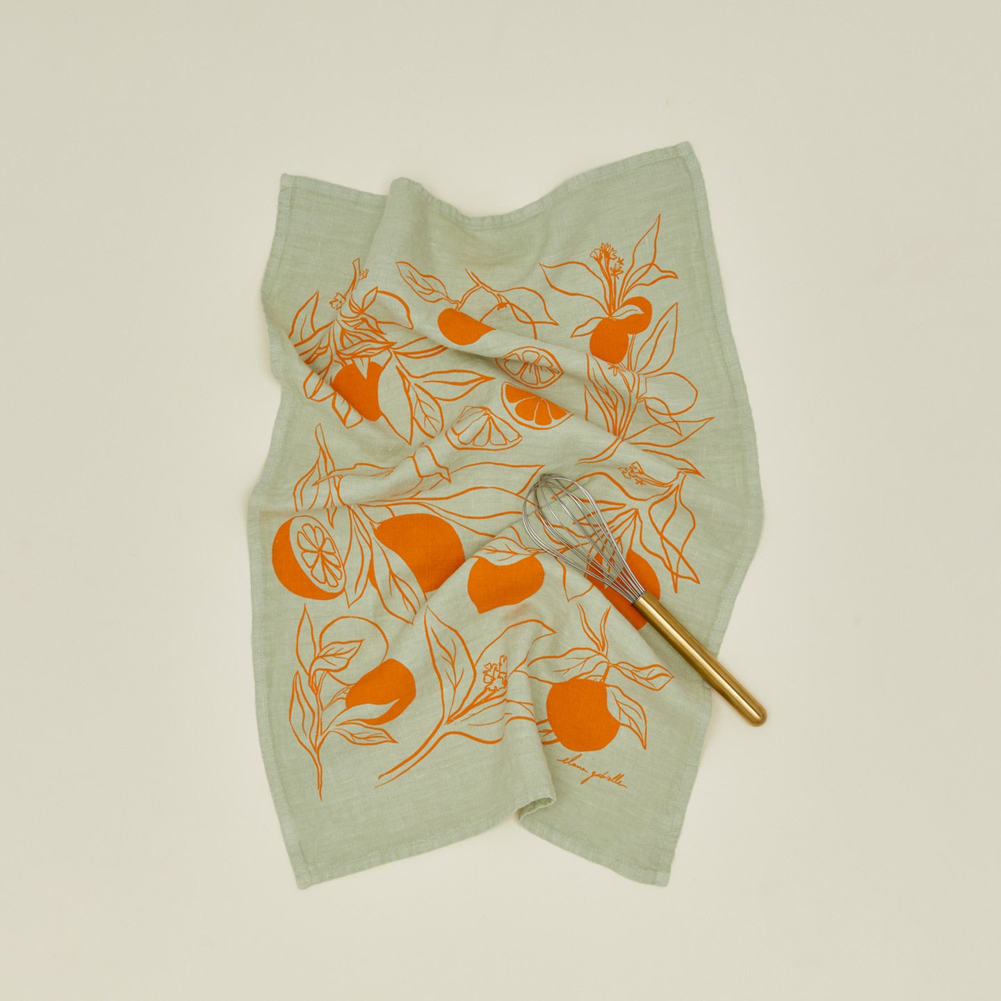 Clementine tea towel with brass handled whisk.