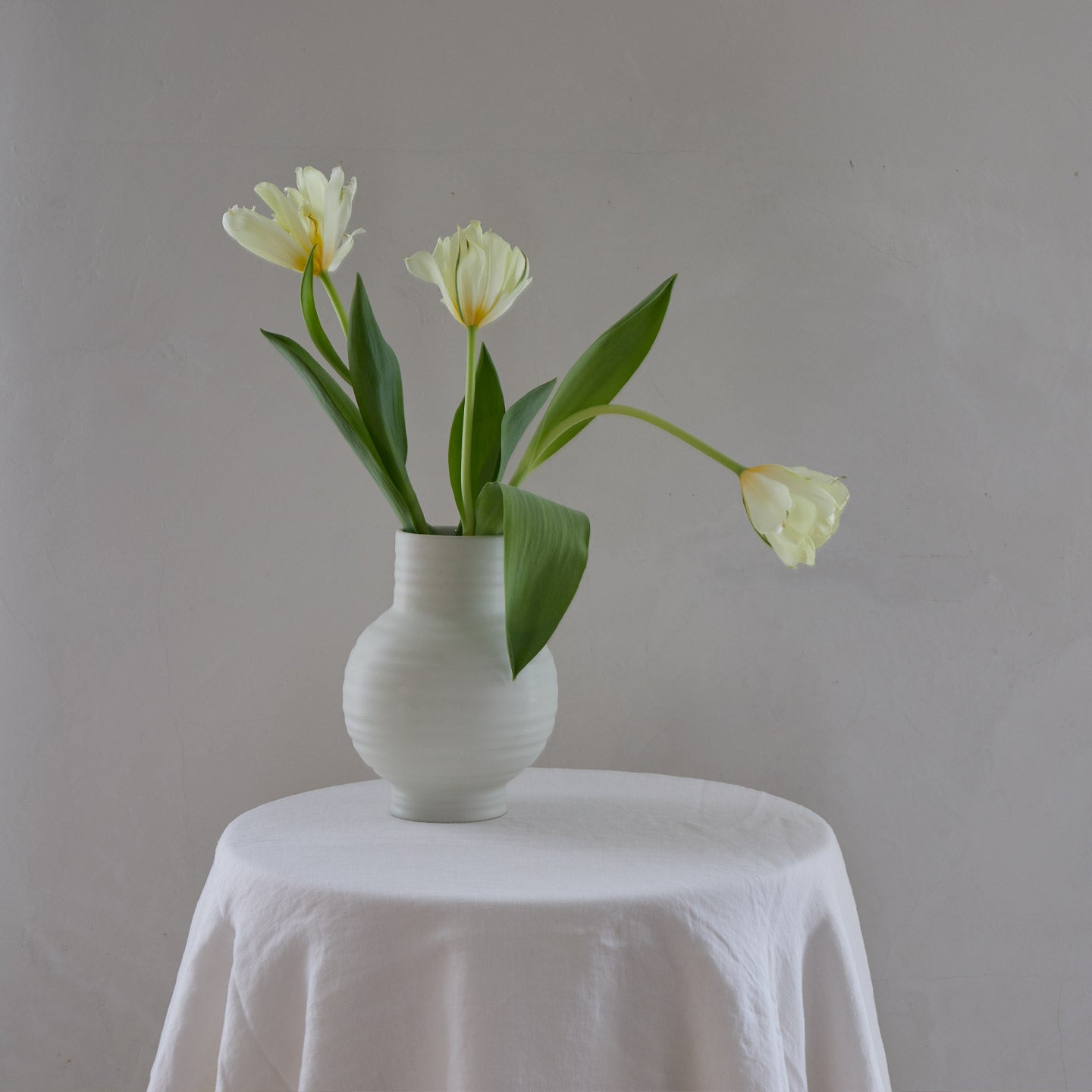Essential Vase in Bone with Flowers on table.